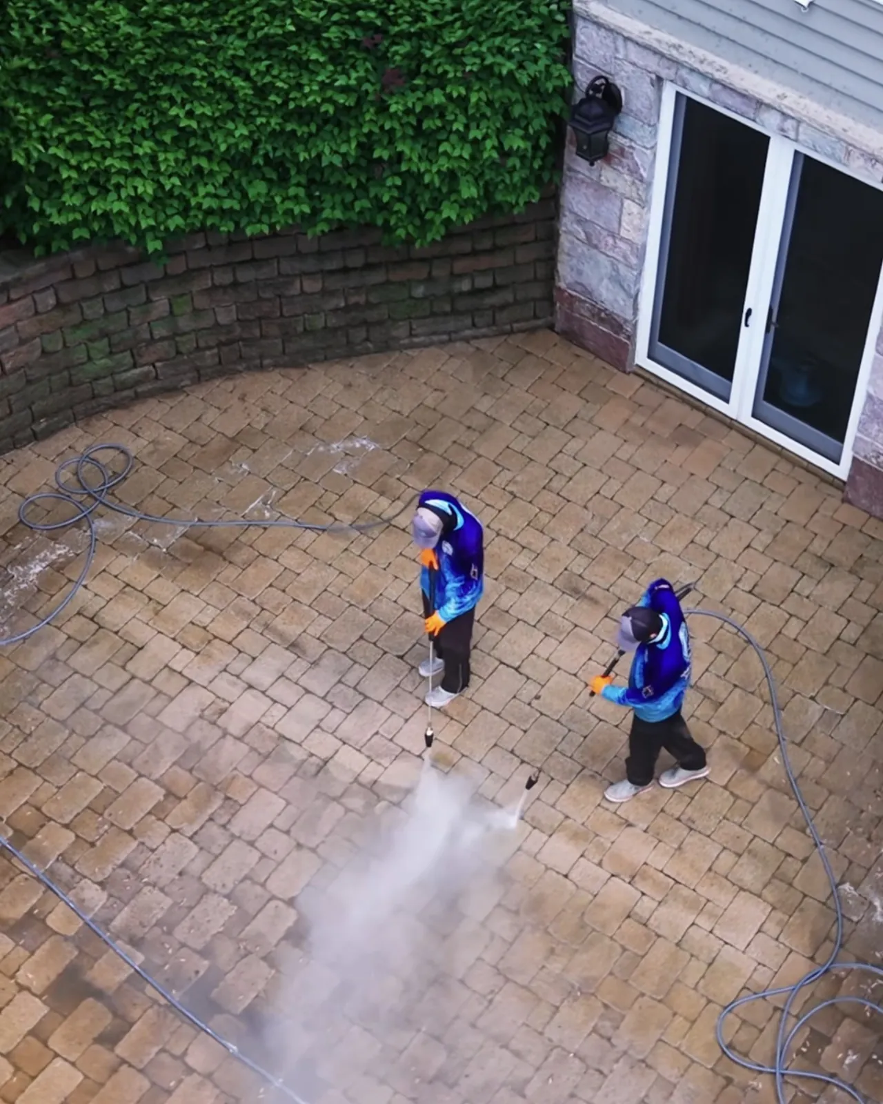 Two crew washing a paver courtyard, from above